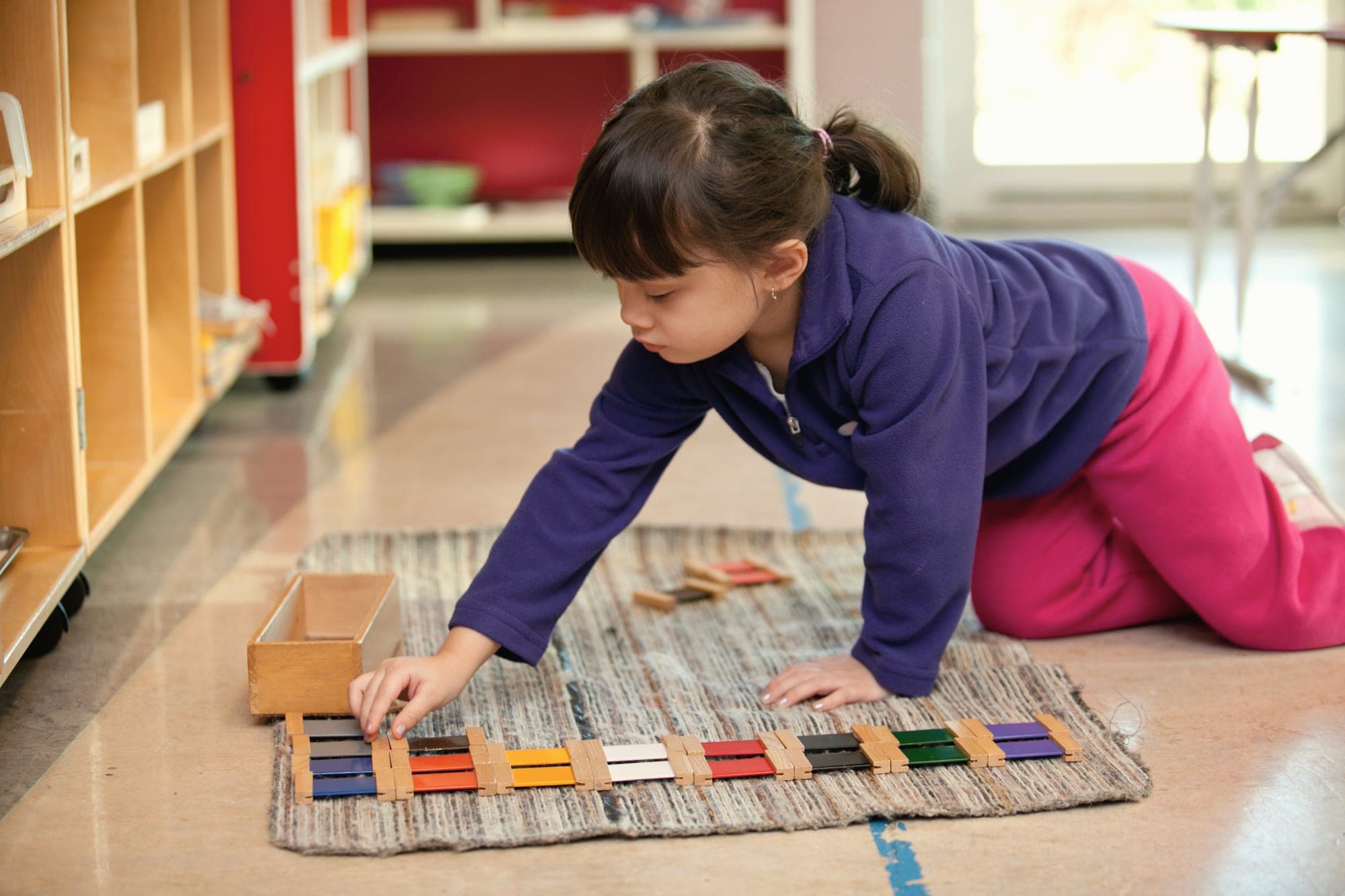 A child arranging Montessori colour tablets on a mat