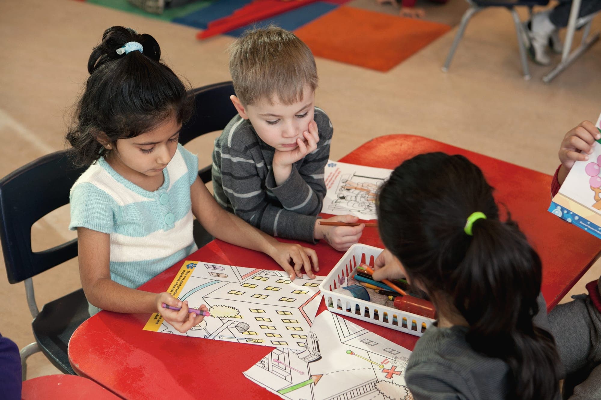 Children colouring together at a classroom table