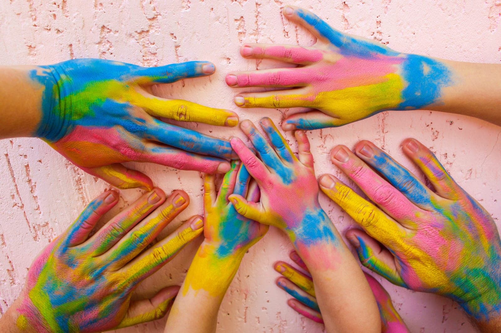 Children’s hands covered in bright paint on a table