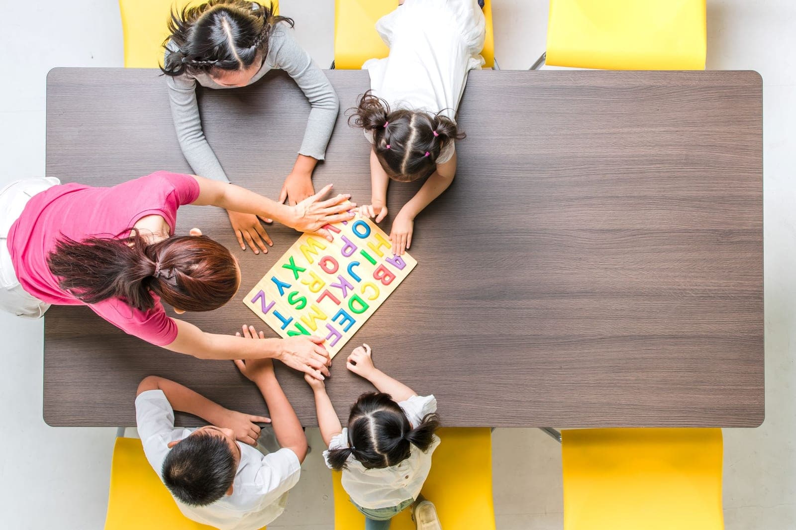 Children working together on an alphabet puzzle at a classroom table