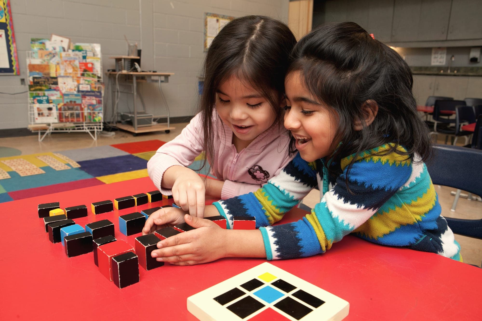 Two preschoolers laughing together while working with Montessori knobless cylinders