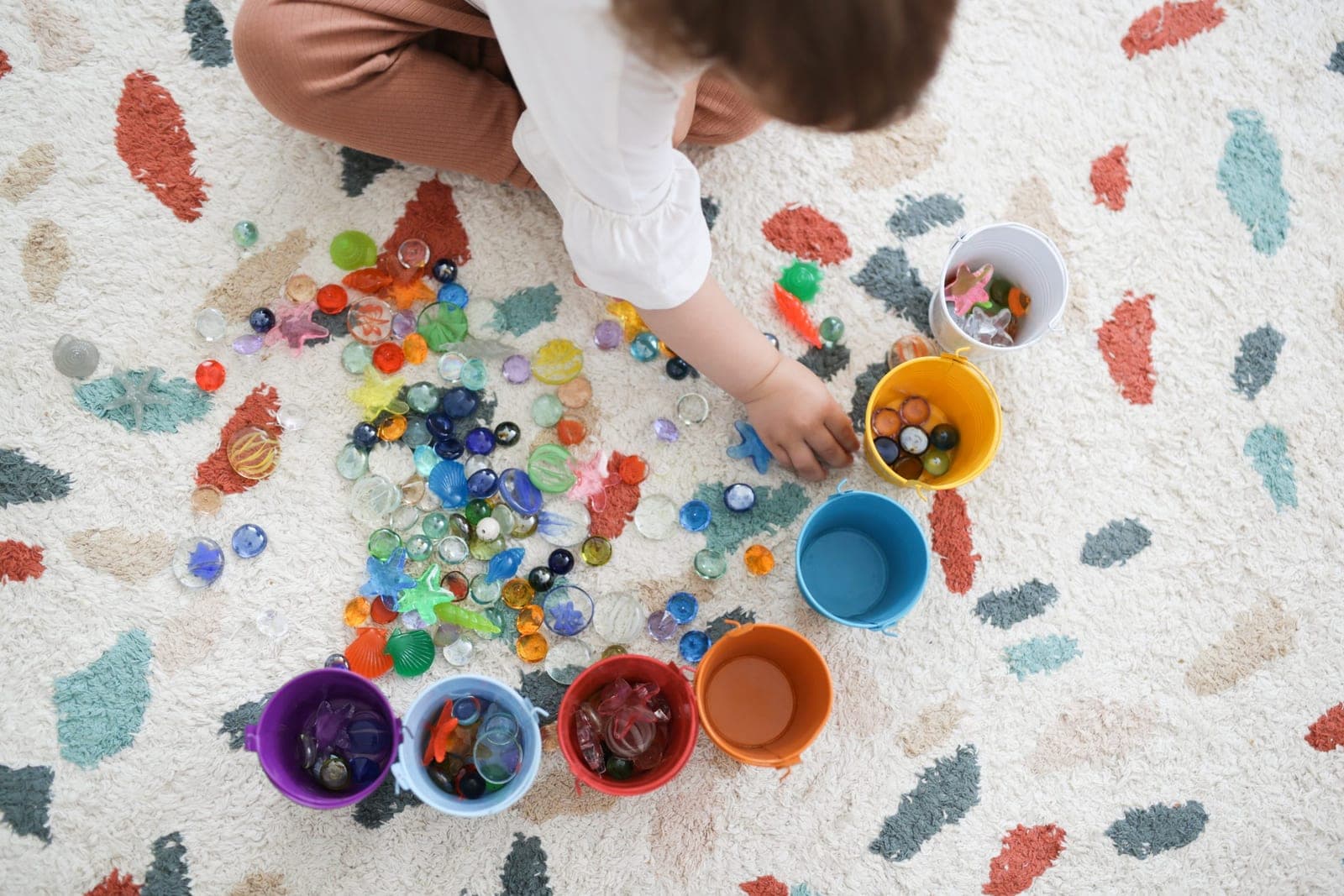 A child sorting coloured beads into small cups