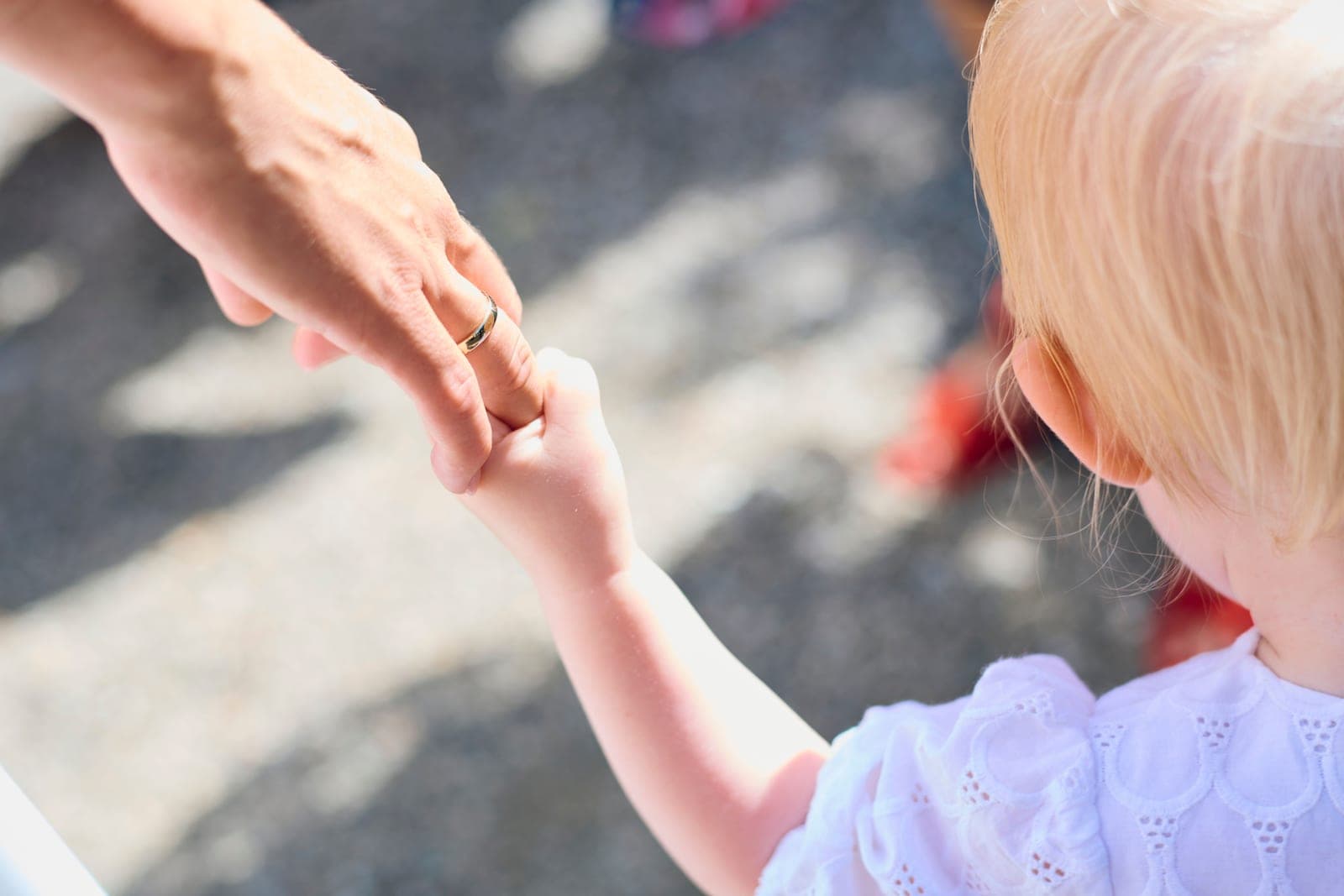 An adult reaching down to take a young child’s hand on arrival