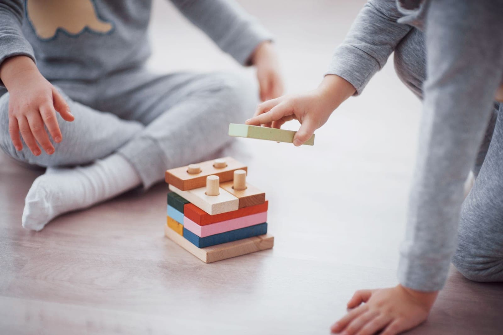 A child's hands building with a wooden stacking toy